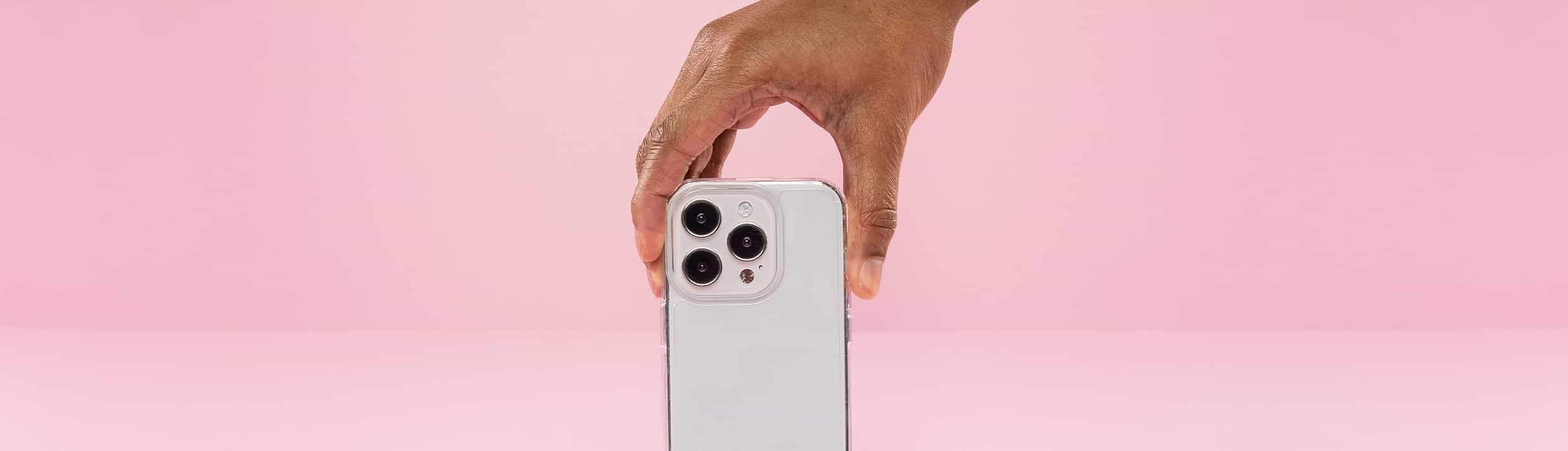 La coque de t&eacute;l&eacute;phone transparente est au centre et est tenue par une main venant du haut.