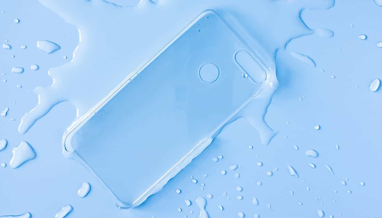 Une coque de t&eacute;l&eacute;phone transparente est pos&eacute;e dans une flaque d'eau avec des &eacute;claboussures autour.