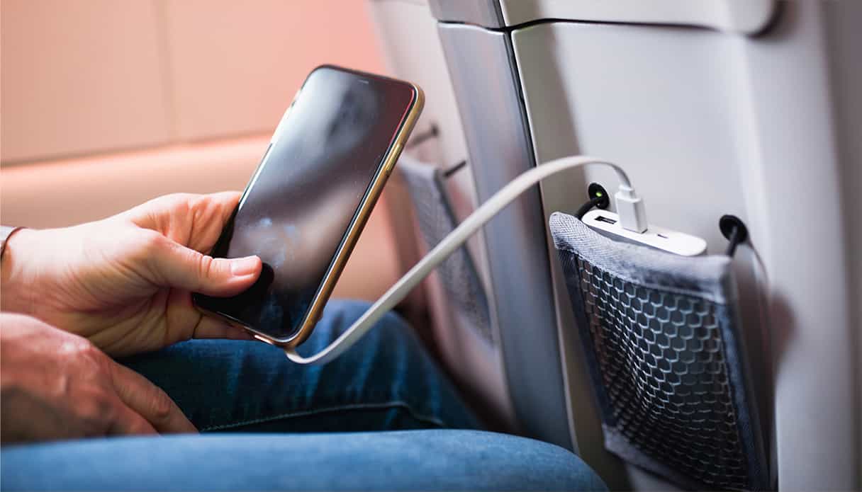 Le téléphone est dans la main du passager et sa batterie externe est dans la poche du siège devant elle.