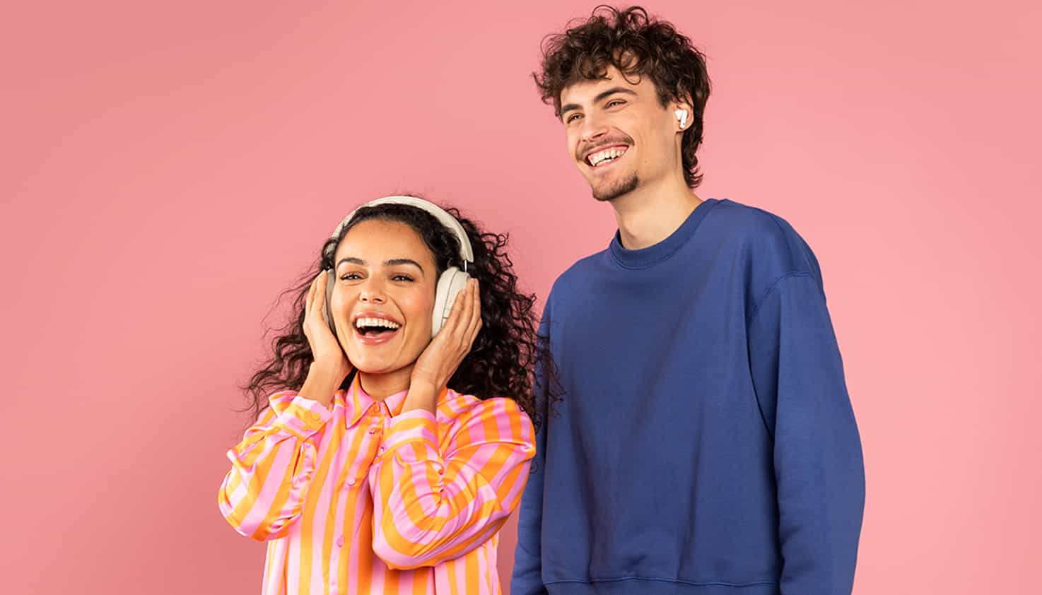 Fond rose avec deux mod&egrave;les souriants, une femme avec un casque et un homme avec des &eacute;couteurs.