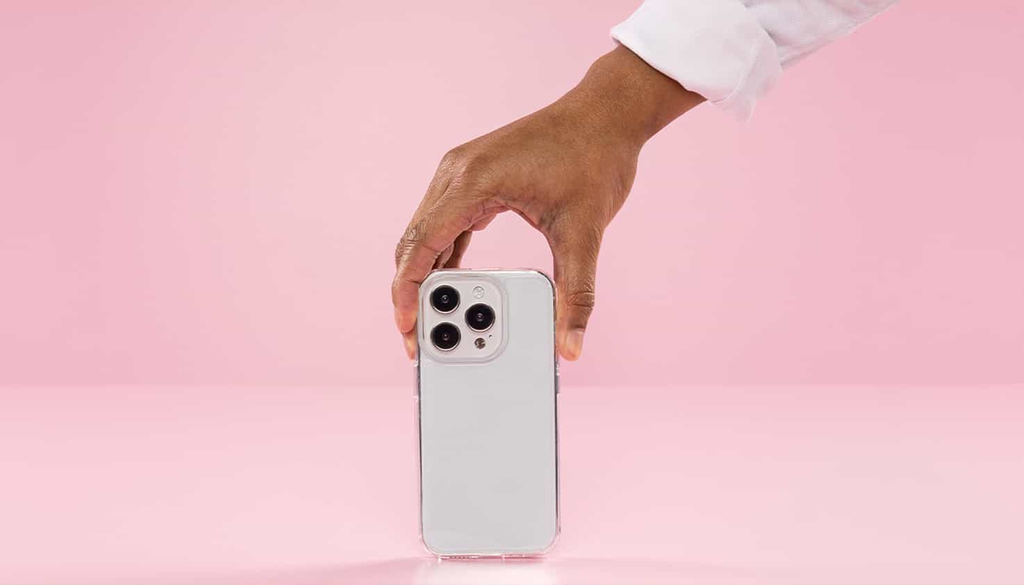 La coque de t&eacute;l&eacute;phone transparente est au centre et est tenue par une main venant du haut.
