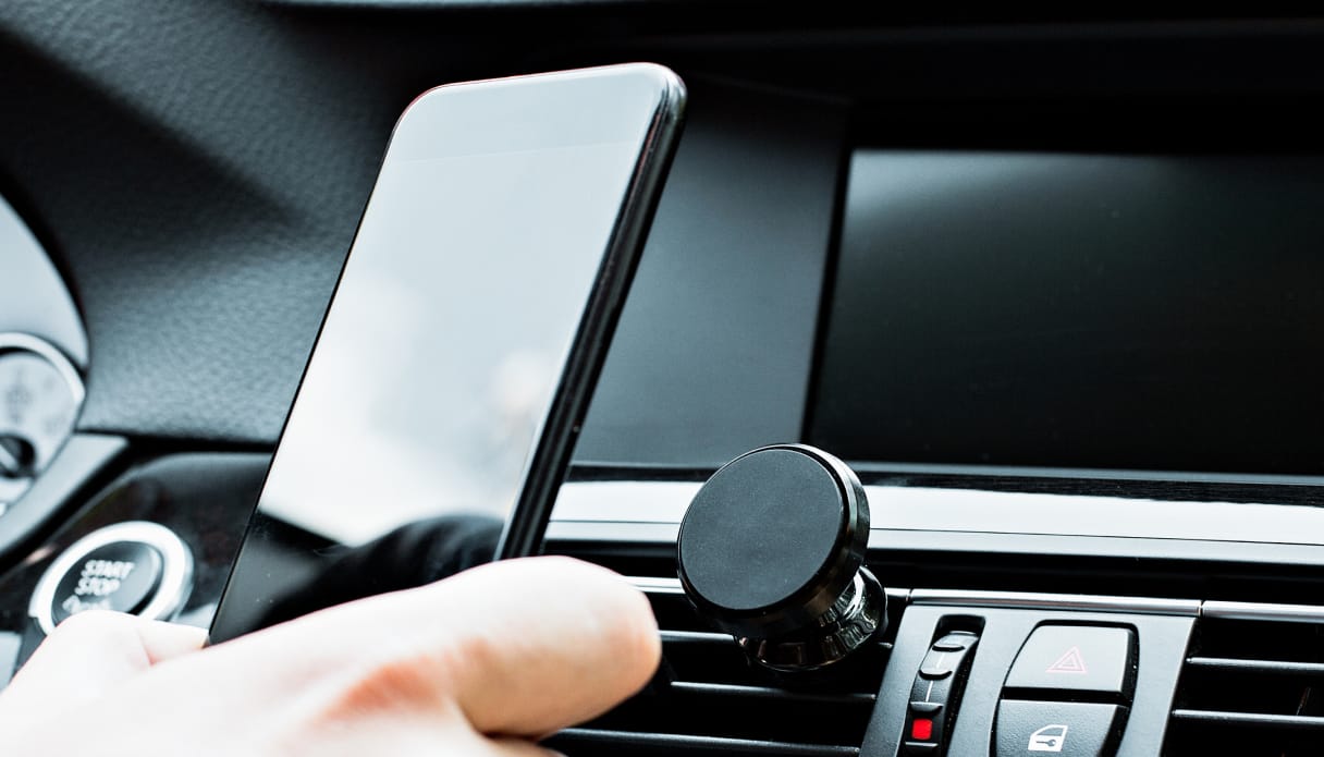 Quelqu'un dans la voiture tient le t&eacute;l&eacute;phone avec des supports. 