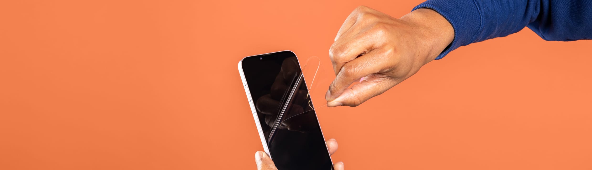 Vous voyez une main retirer un protecteur d'écran d'un smartphone.