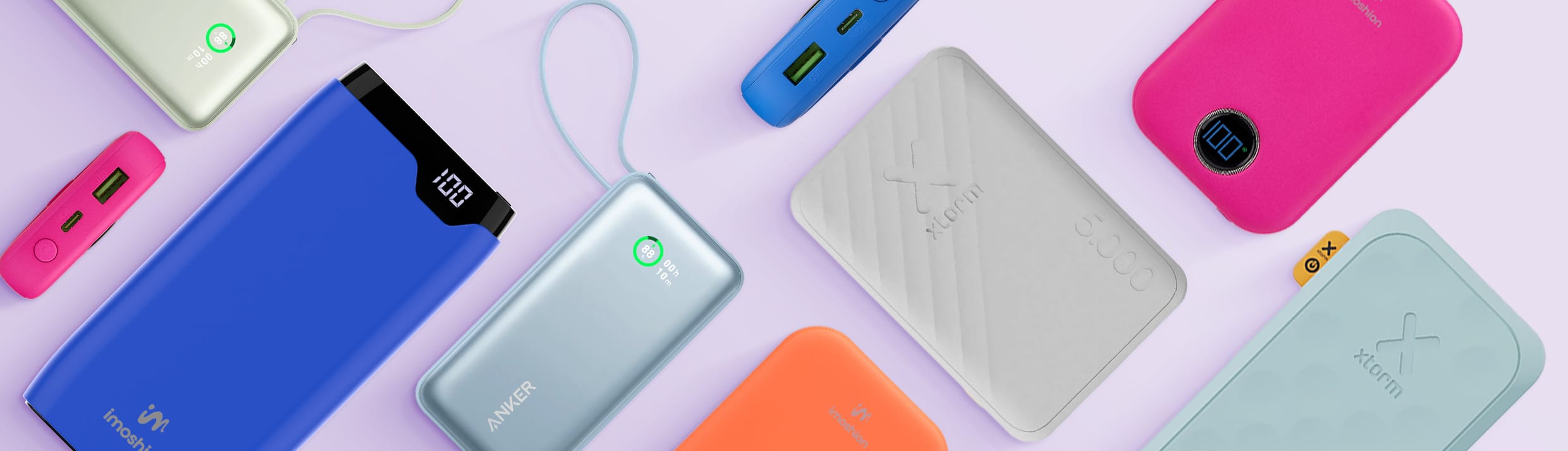 Un aperçu des différentes marques, tailles, couleurs et types de batteries externes, certaines posées à plat, d’autres sur le côté. Notamment des batteries externes Anker, Xtorm et imoshion, sur un fond violet clair.