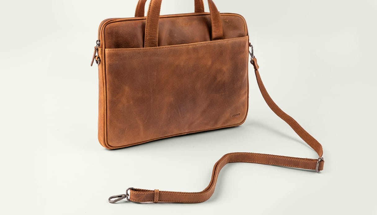 Un sac pour ordinateur portable couleur cognac avec une bandoulière.