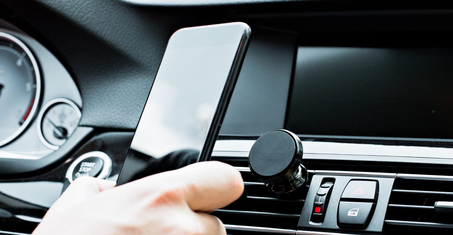 Une personne fixe un t&eacute;l&eacute;phone sur un support magn&eacute;tique.
