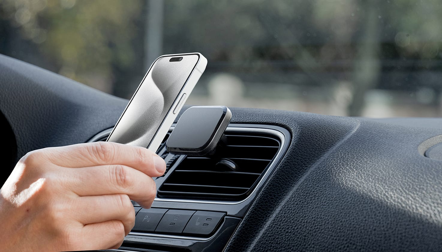 Quelqu&rsquo;un place un t&eacute;l&eacute;phone sur un support MagSafe pour voiture.