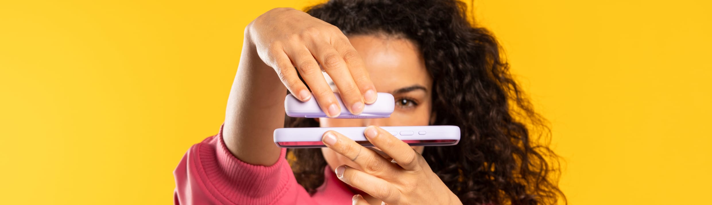 Une femme connecte une batterie externe &agrave; son t&eacute;l&eacute;phone &agrave; l'aide de MagSafe.